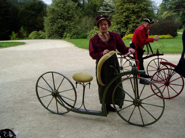 Lady in Regency dress next to a lady's velocipede